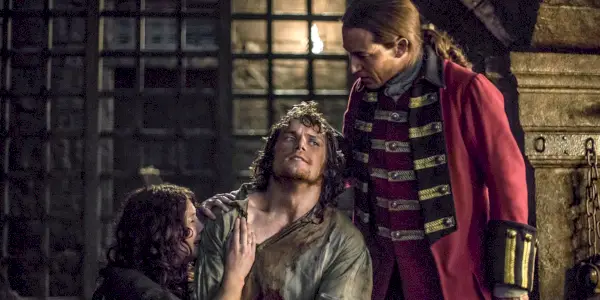 Claire græder, mens Jamie holdes af Black Jack Randall i Outlander sæson 1
