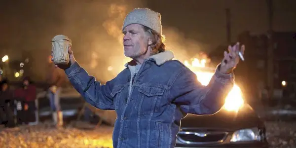 Frank Gallagher (William H. Macy) debout devant une voiture en feu dans Shameless
