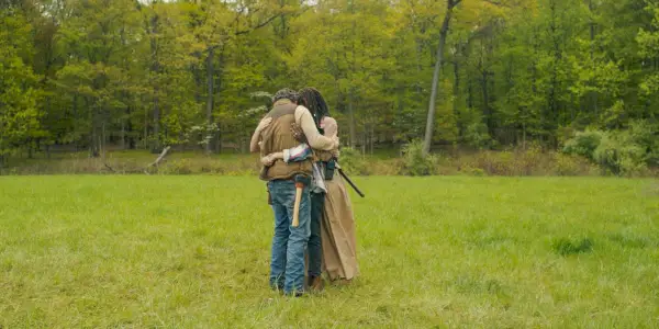 Rick e Michonne abraçando seus filhos em um campo aberto em The Walking Dead: The Ones Who Live.
