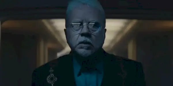 Bernard (Tim Robbins) ser i frykt på skjermen i sitt seremonielle antrekk i Silo