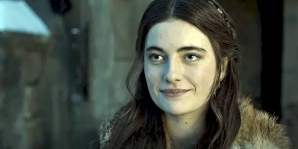 Millie Brady uśmiecha się do kogoś poza ekranem jako Aethelflaed w scenie z Ostatniego królestwa
