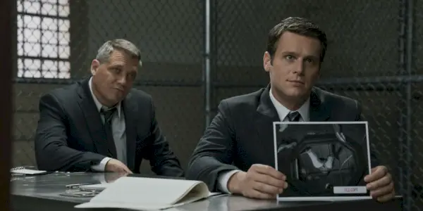 Jeden muž drží obrázok mŕtveho tela, zatiaľ čo druhý sa pozerá na Mindhunter.
