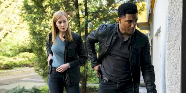 Eva-Jane Willis como agente da Europol Megan Smitty Garretson e Carter Redwood como agente especial Andre Raines se aproximando de uma porta em FBI: International temporada 3, episódio 11