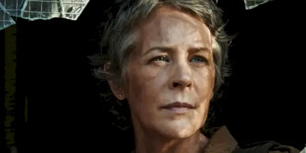 Carol regarde à travers une vitre brisée dans The Walking Dead