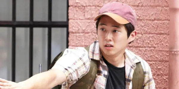 Steven Yeun som Glenn fra sæson 1 af The Walking Dead, iført baseballhat og rygsæk.