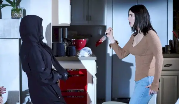 B&B, Steffy choquée se tient dans sa cuisine avec un couteau ensanglanté, regardant Sheila emmitouflée dans sa capuche en face d'elle.