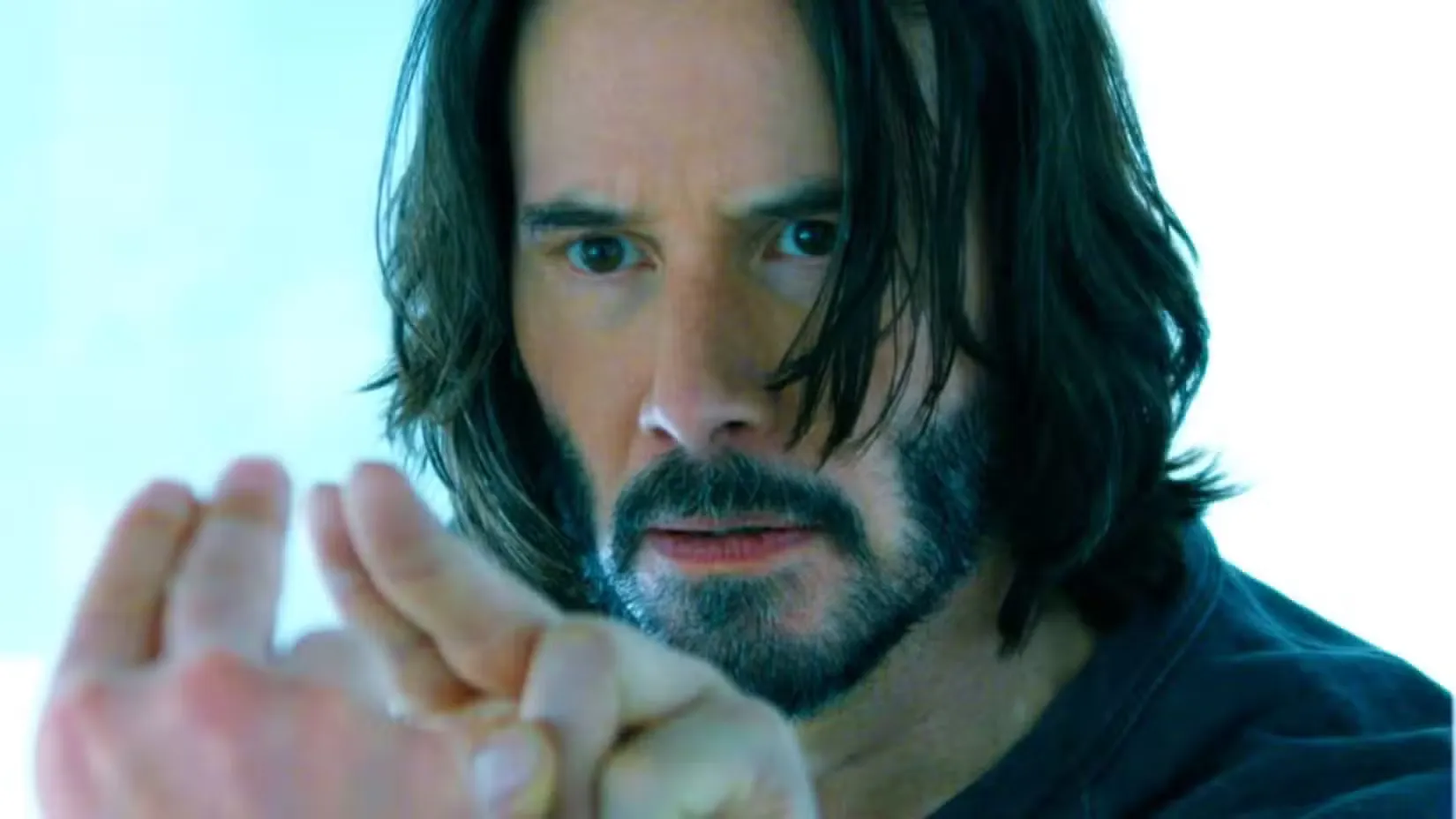 Кіану Рівз у ролі Нео тримає два пальці біля дзеркала у фільмі 