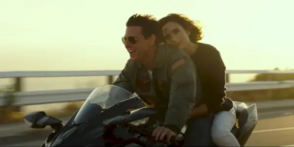 Tom Cruise se ríe mientras conduce una motocicleta con Jennifer Connelly en Top Gun Maverick