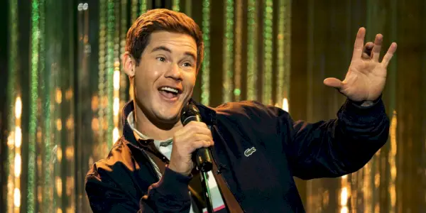 Adam DeVine tient un micro et chante sur scène dans le rôle de Bumper Allen dans le spin-off Pitch Perfect Bumper à Berlin