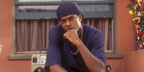 Chris Tucker sitter og legger knyttneven under munnen og tenker på fredag