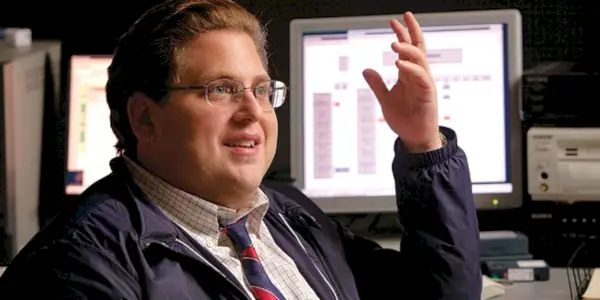 Jonah Hill jako Peter Brand uśmiecha się i podnosi rękę w Moneyball