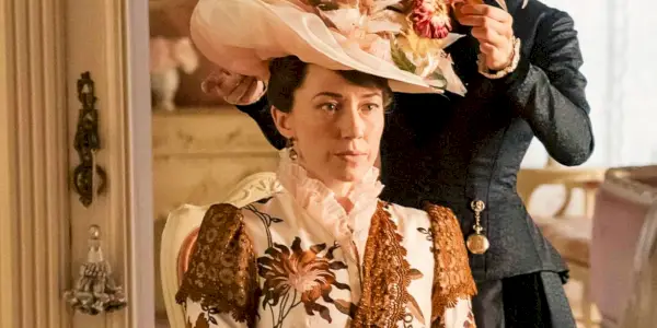 Carrie Coon nei panni di Bertha Russell seduta davanti a uno specchio mentre una cameriera si aggiusta il cappello in The Gilded Age