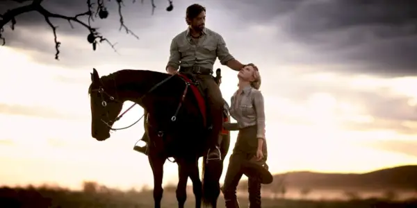 Nicole Kidman steht neben Hugh Jackman zu Pferd, während die Sonne über dem Outback in Australien (auch bekannt als Faraway Downs) untergeht.